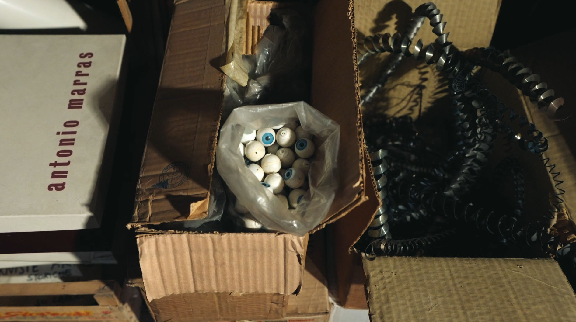 Pappkisten, die mit künstlichen Augen und anderen Arbeitsutensilien gefüllt sind.